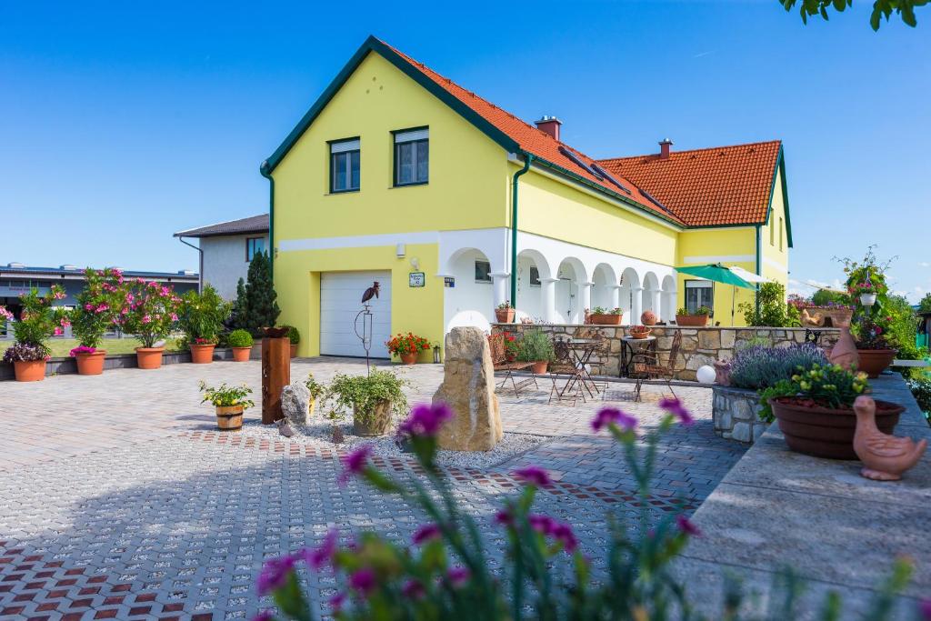 ein gelbes Haus mit Blumen davor in der Unterkunft Appartementhaus Freiler in Mörbisch am See