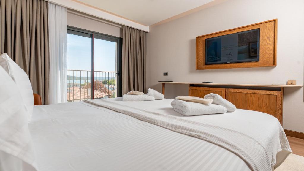 a bedroom with two beds with a tv and a window at Cunda Kızılca Deluxe Hotel & SPA in Ayvalık