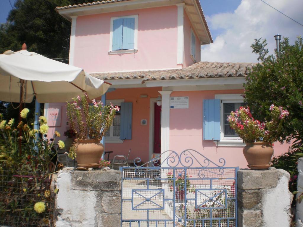 a pink house with a gate in front of it at Aiolos Rooms in Tsoukalades