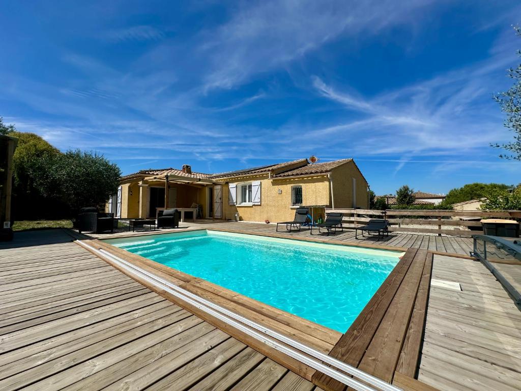 a swimming pool with a wooden deck and a house at Villa FURGY - Climatisation et parking in Carcassonne