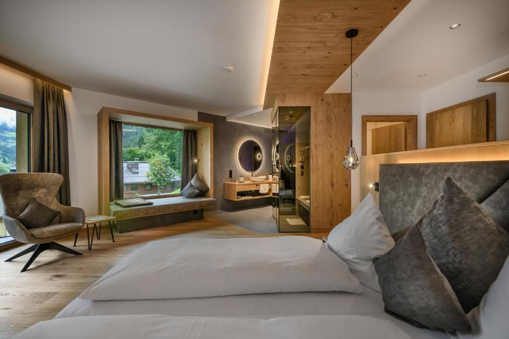 a bedroom with a large white bed and a chair at Hotel Hubertushof in Grossarl