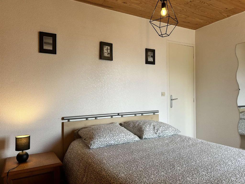 Un dormitorio con una cama y una lámpara sobre una mesa. en 767 - Maison dans un lieu calme à 850m de la plage, en Erquy