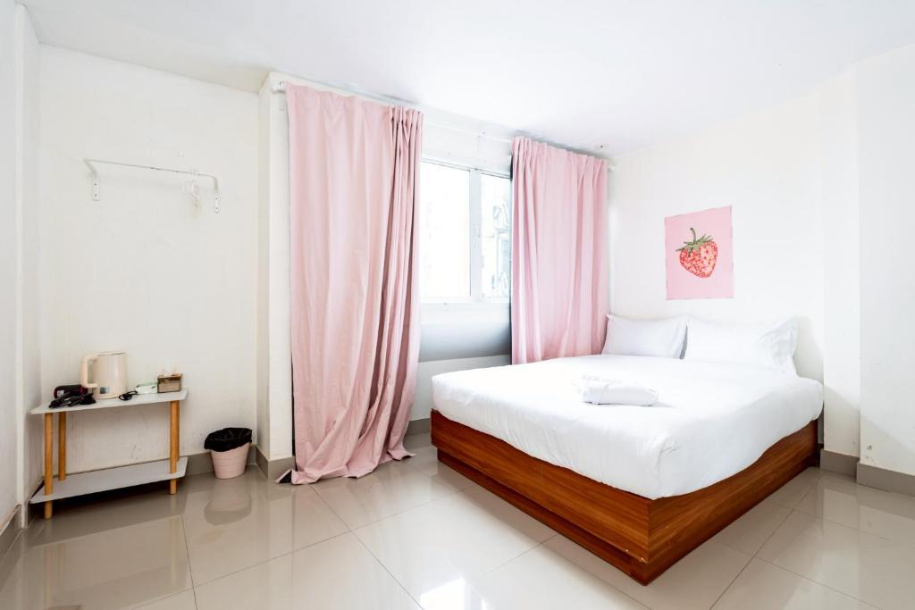 a bedroom with a white bed with pink curtains at Oh My Nap Sukhumvit 3 Nana station -โอ้ มาย แนป สุขุมวิท ซอย3 รถไฟฟ้านานา in Bangkok