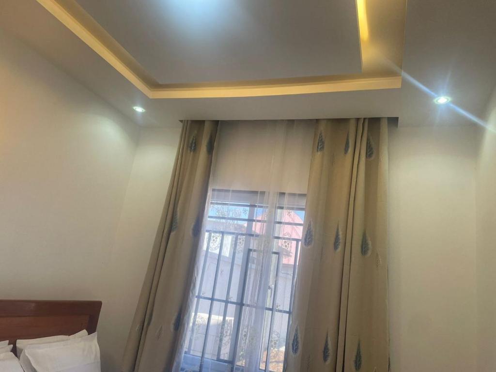 a room with a window with a curtain and a bed at La Million Palace - Dodoma in Dodoma
