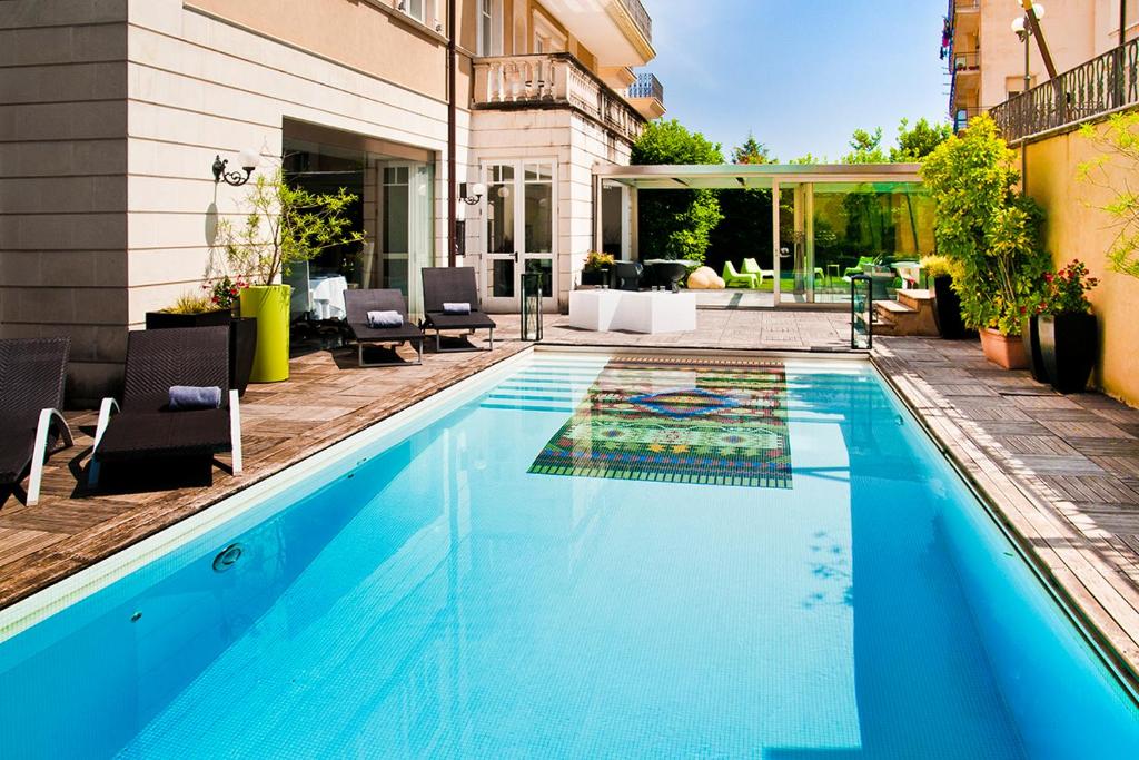 a swimming pool with chairs and a house at Hotel Villa del Bosco in Catania
