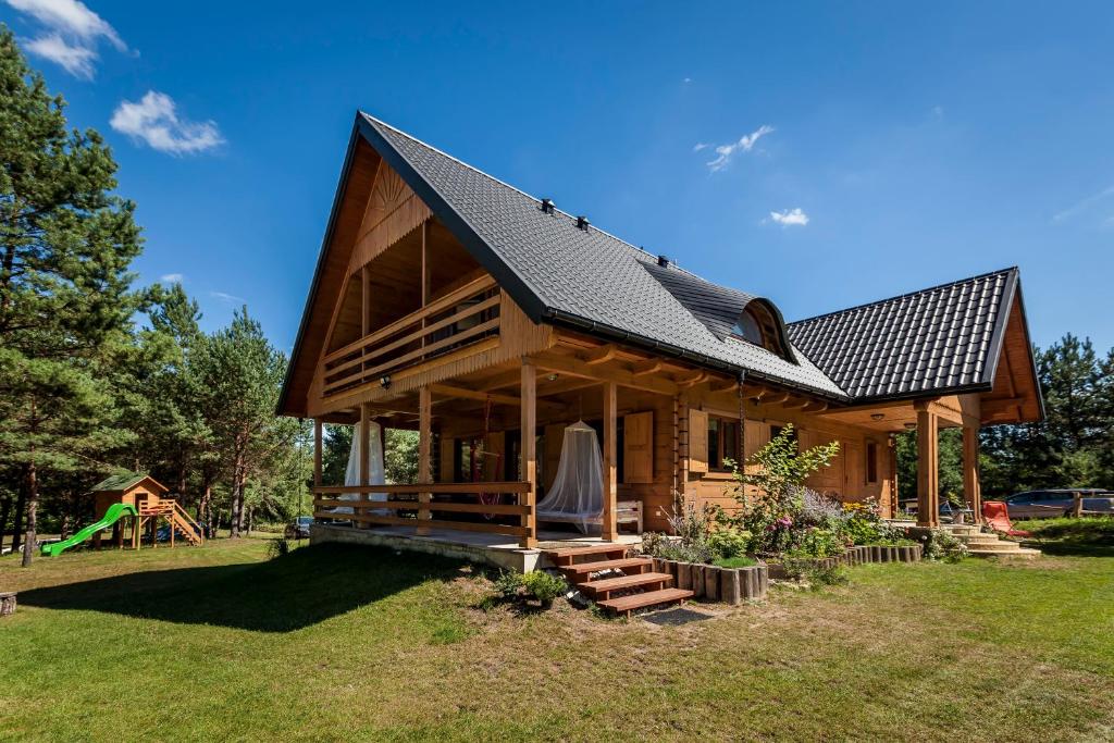 a log cabin with a black roof and a playground at Willa Pasym in Pasym