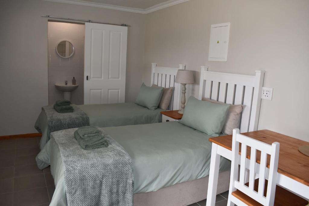 a bedroom with two beds and a table and a lamp at Nuwepos in Vanrhynsdorp