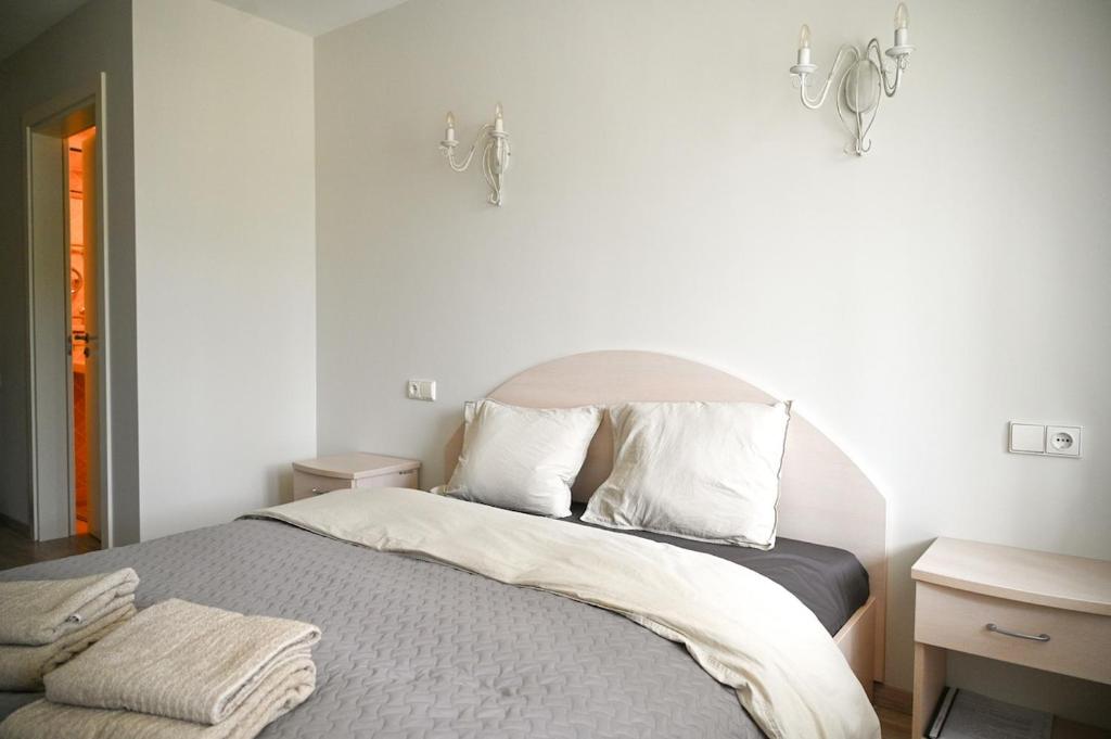 a bedroom with a bed with white sheets and pillows at Giruliai Holiday Apartments - XIV by Prime Rentals in Melnragė