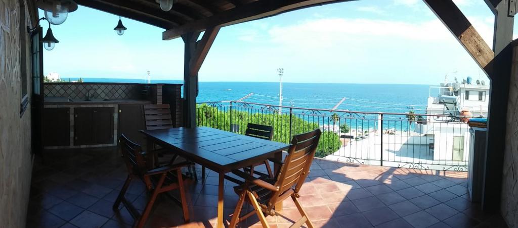 een tafel en stoelen op een balkon met uitzicht op de oceaan bij Le Spiagge in Letojanni