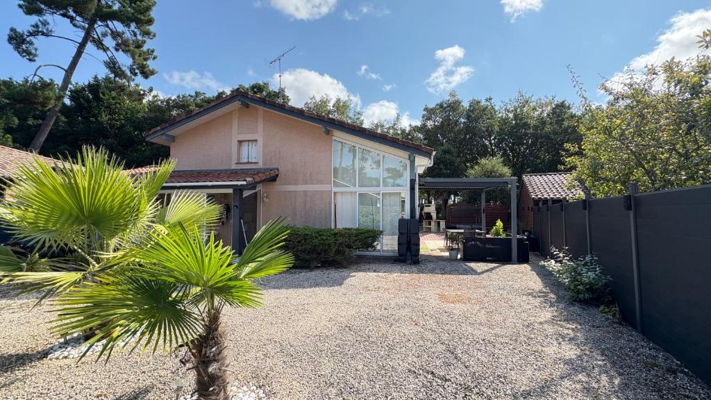 a house with a fence and a palm tree at Villa Indépendante tout confort Soustons Plage Golf à 900m wifi Bbq in Soustons