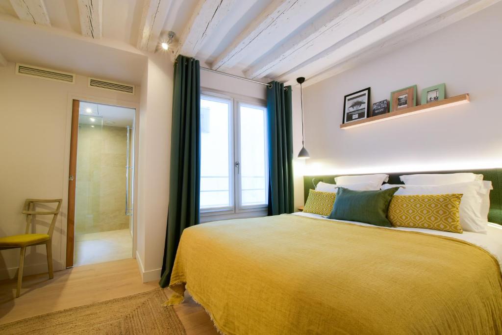 sypialnia z dużym łóżkiem i oknem w obiekcie Victoire & Germain w Paryżu