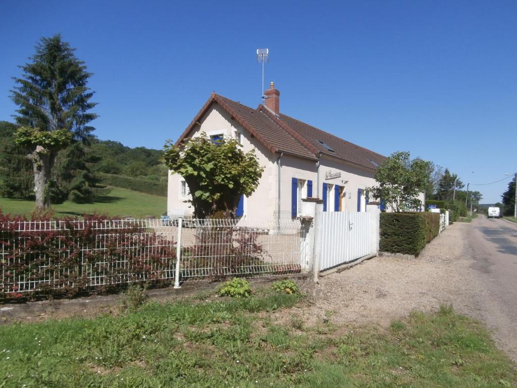 een wit huis met een hek naast een weg bij La Parisienne des Amognes in Montigny-aux-Amognes