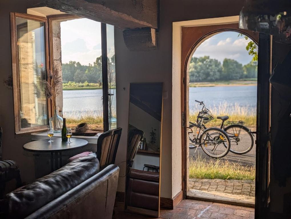 a room with a table and a view of a lake at Maison de marinier les pieds dans l'eau face à la Loire in Sully-sur-Loire