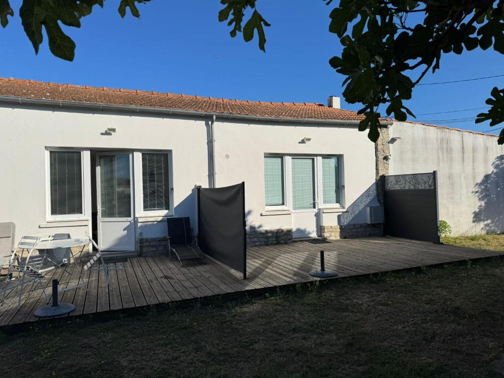 ein Haus mit einer Holzterrasse mit einem Tisch und Stühlen in der Unterkunft LES TRÉMIÈRES N°1 - A 5MN DES PLAGES A VELO in La Michelière