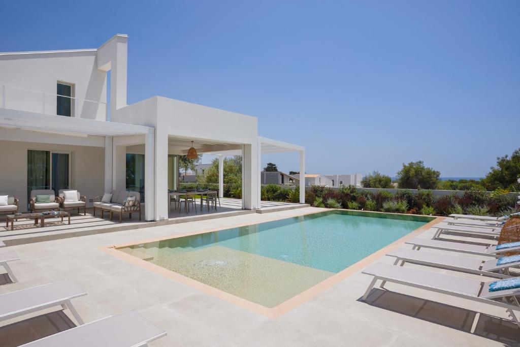 a villa with a swimming pool and lounge chairs at Villa Mareiva - Heated Pool, Beach 150 mt in Pozzallo