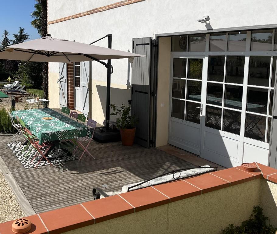 eine Terrasse mit Tisch und Sonnenschirm in der Unterkunft Maison Villa Santina in Piquecos