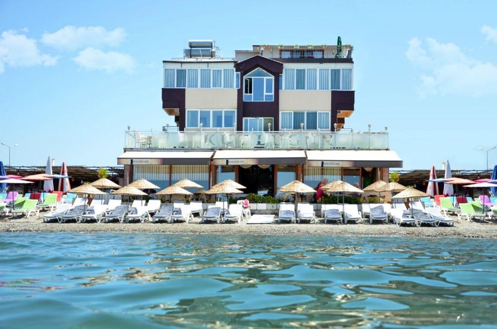 un hotel en la playa con sillas y sombrillas en Kutlugun Sahil Otel, en Akçay