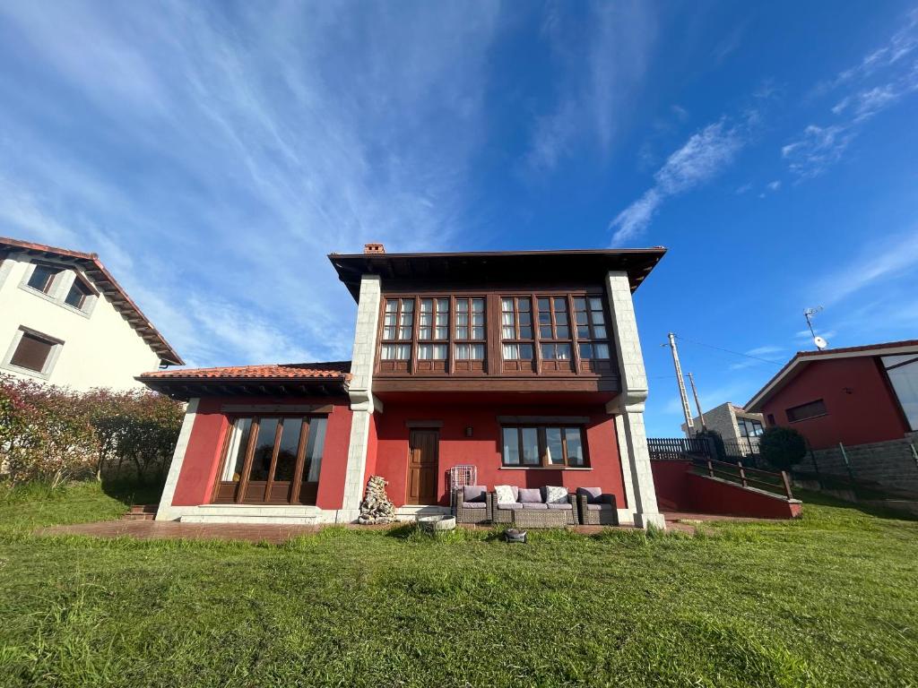 ein rotes Haus auf einer grünen Wiese mit blauem Himmel in der Unterkunft La casa roja de Ovio in Picones