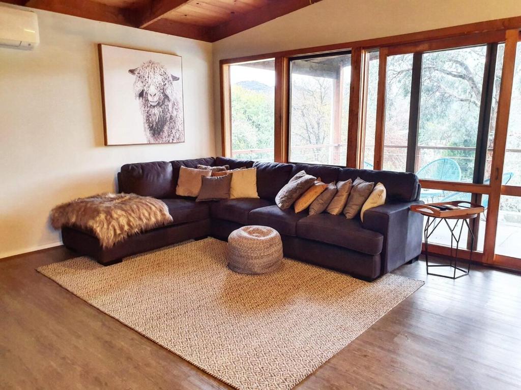 ein Wohnzimmer mit einem schwarzen Ledersofa und einem Teppich in der Unterkunft Howqua Inlet Country Home in Howqua