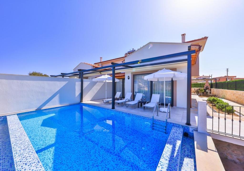 a swimming pool with two chairs and a house at Villa Safran in Kas