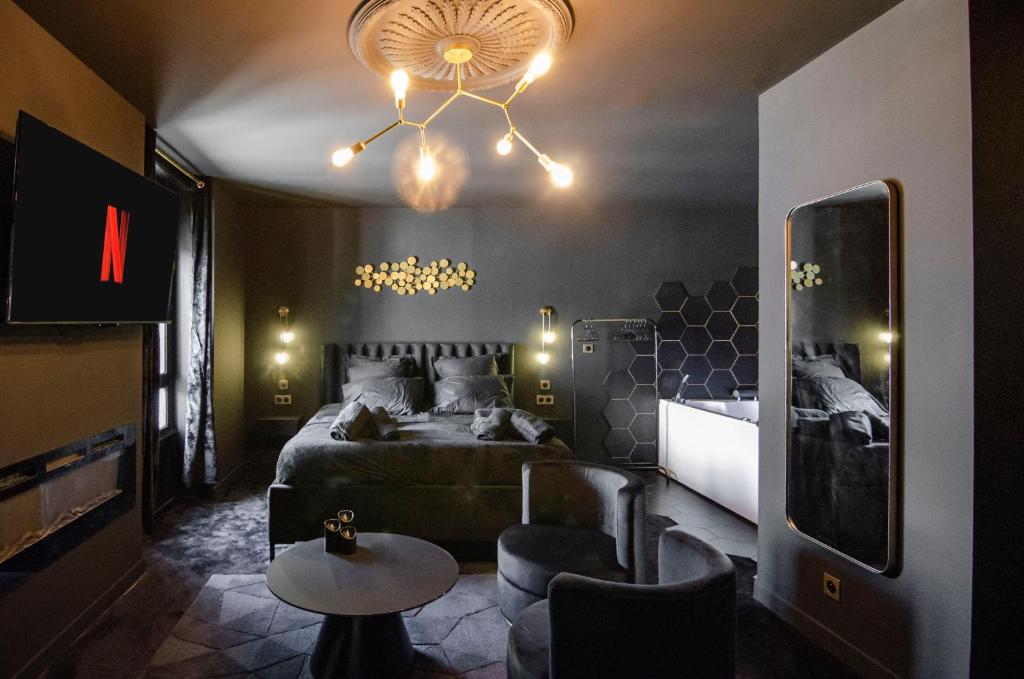 una camera da letto con un letto e un lampadario di Suite Balneo Hammam Noire et Or a Saint-Étienne