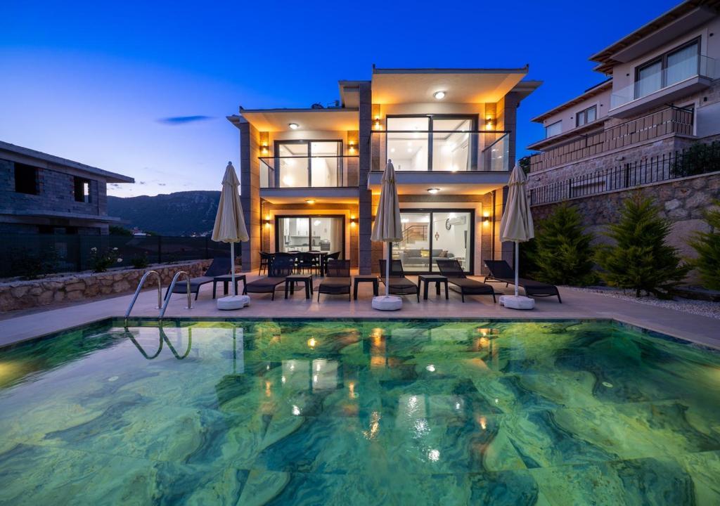 a house with a swimming pool in front of a house at Villa Poyraz in Kas