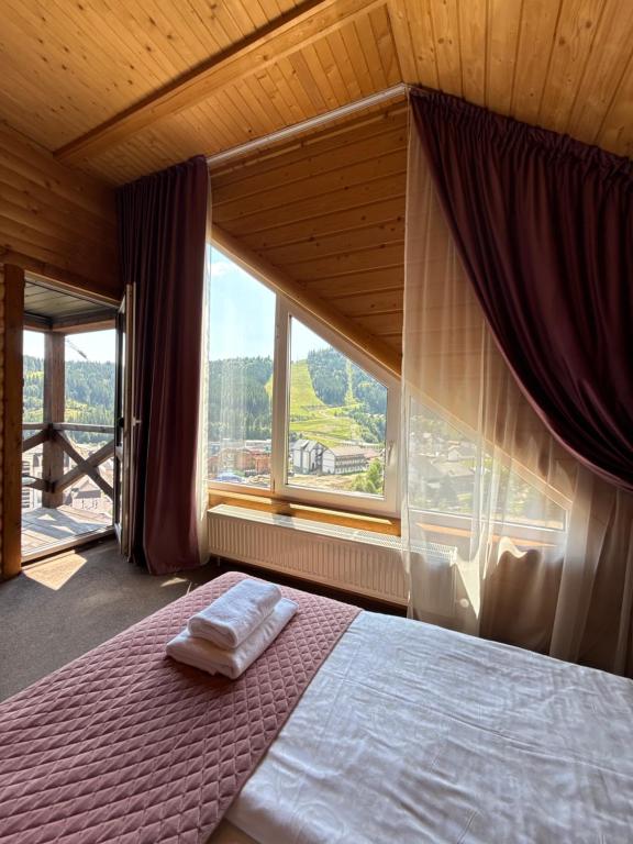 een slaapkamer met een bed met een groot raam bij Панорама гір in Boekovel