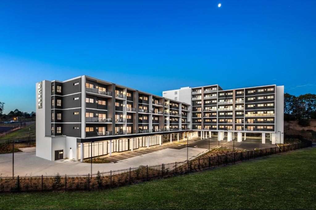 um grande edifício de apartamentos com luzes acesas em Quest Bella Vista em Baulkham Hills