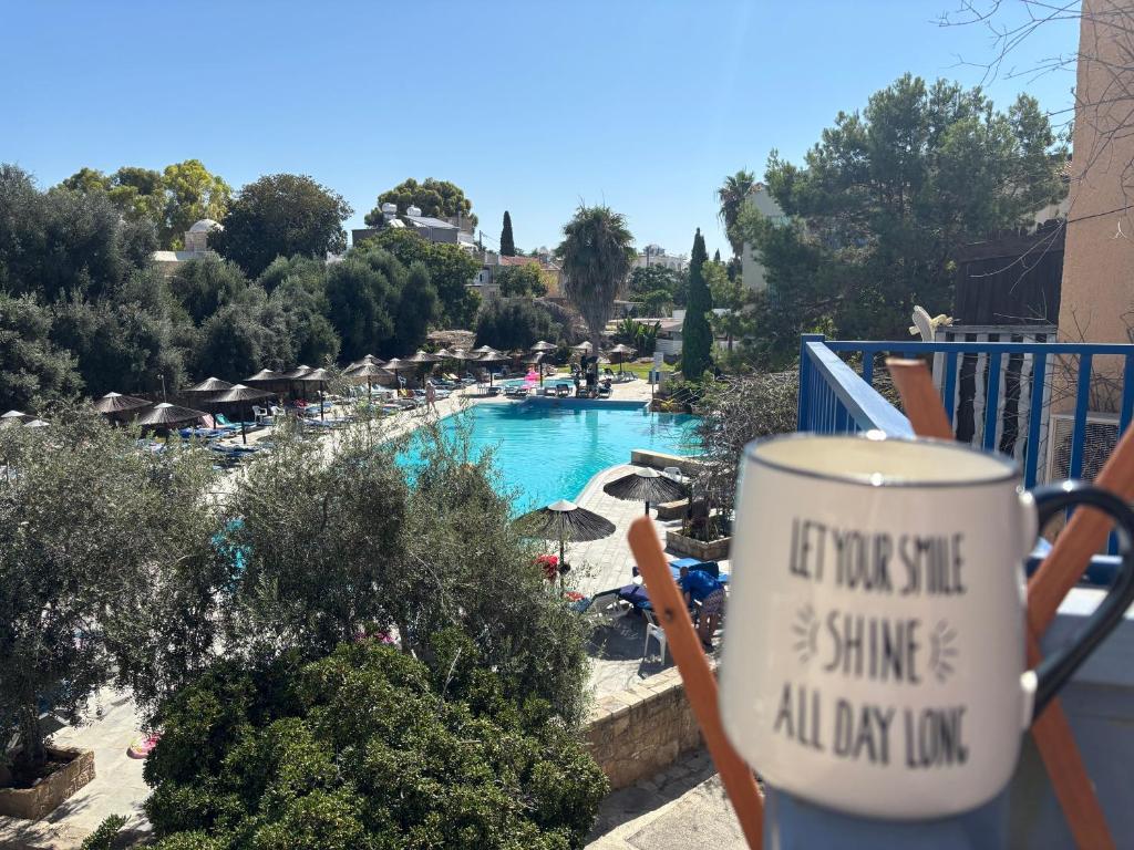 a cup of coffee sitting on a balcony next to a pool at Modern Apt in Paphos Port - pool & 50 m to the sea in Paphos City