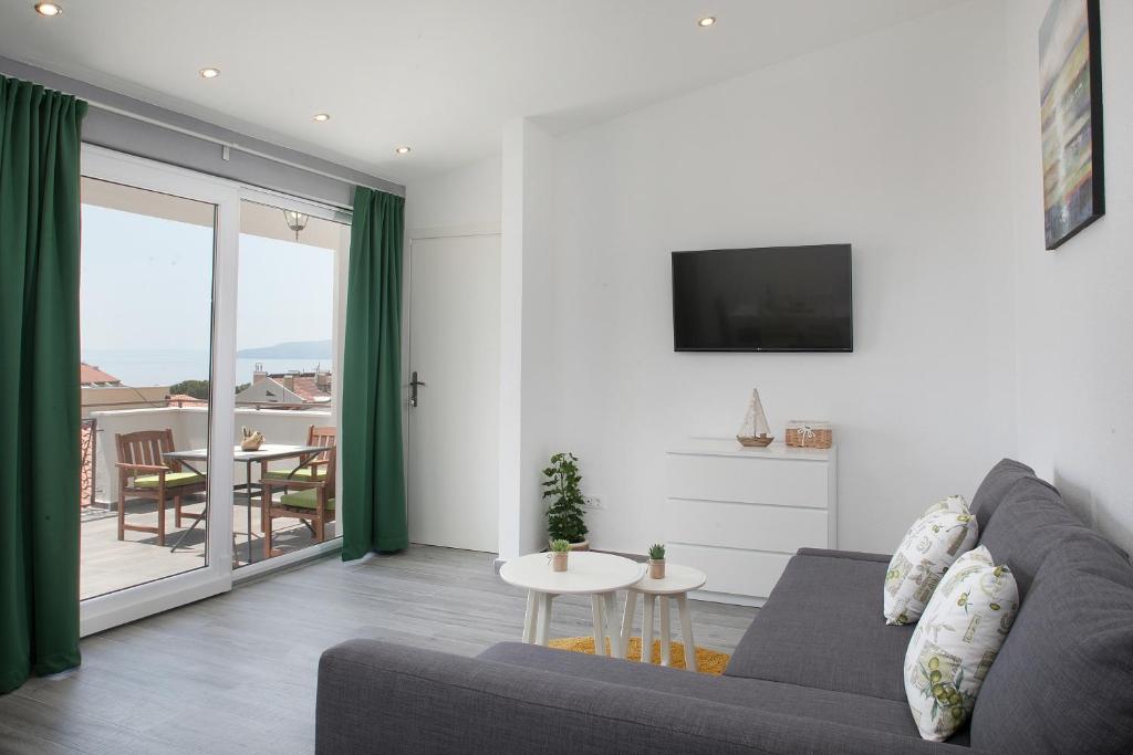 a living room with a couch and a tv and a table at Apartment Luka in Makarska