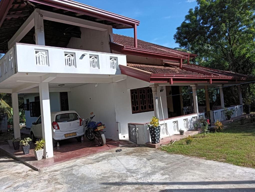 a white house with a car parked in front of it at Villa village guest house in Trincomalee