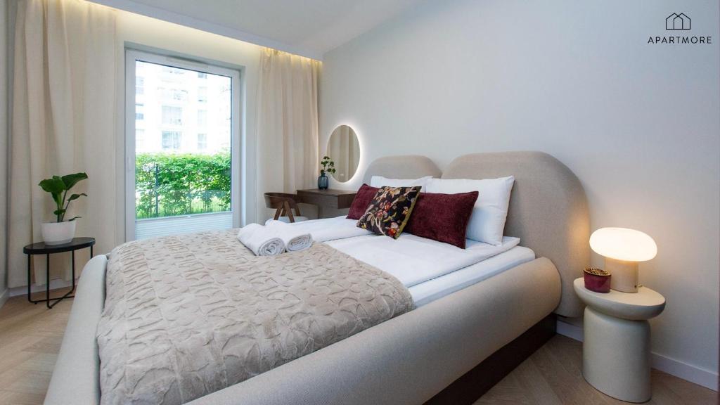 Serene bedroom with rounded beige headboard, textured throw, decorative pillows and glowing bedside lamp