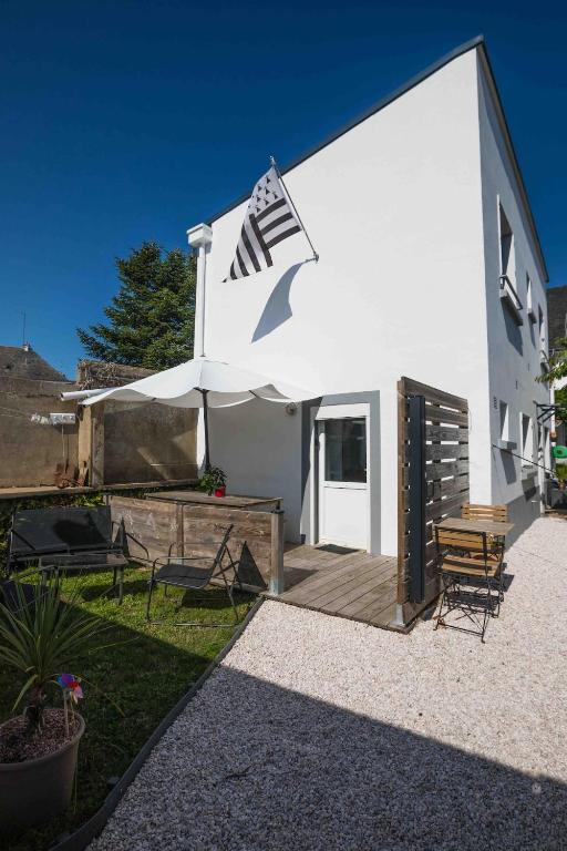 a white building with a deck with a flag on it at Maison proche Naval Group in Lanester