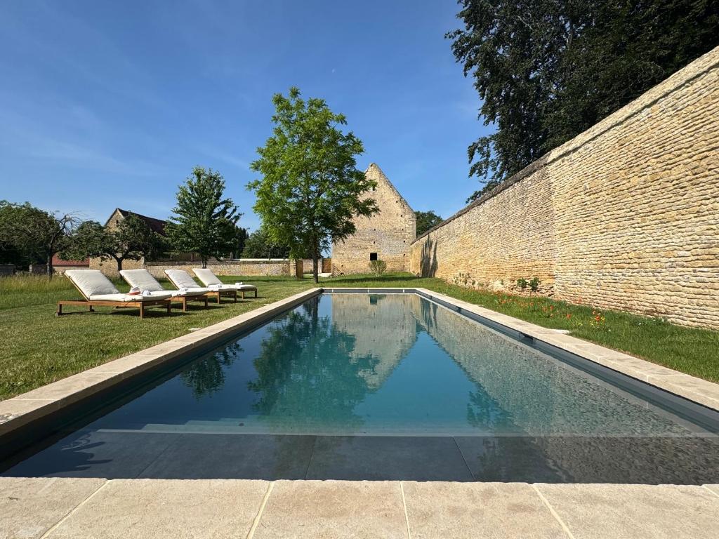 una piscina con due sedie a sdraio e un muro di mattoni di La Ferme du Château de Grisy, Piscine, 10p a Vendeuvre
