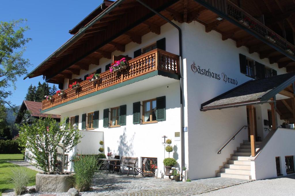 ein weißes Gebäude mit einem Balkon mit Blumen darauf in der Unterkunft Hotel Garni Gästehaus Brand in Bad Wiessee