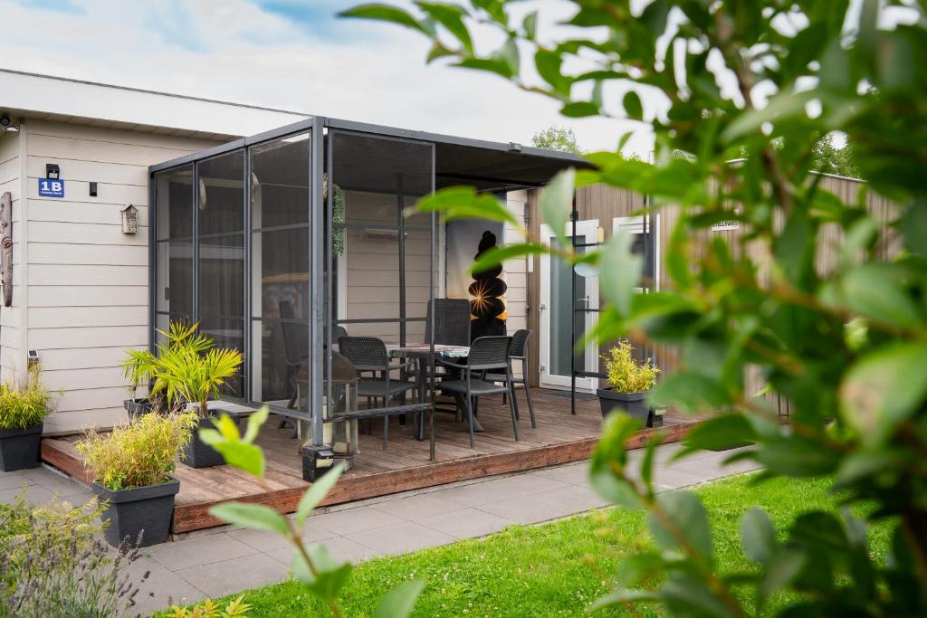 ein Glashaus mit einem Tisch und Stühlen auf einer Terrasse in der Unterkunft Chalet Hart van Zeeland met overdekt terras & natuur VP086 in Heinkensand