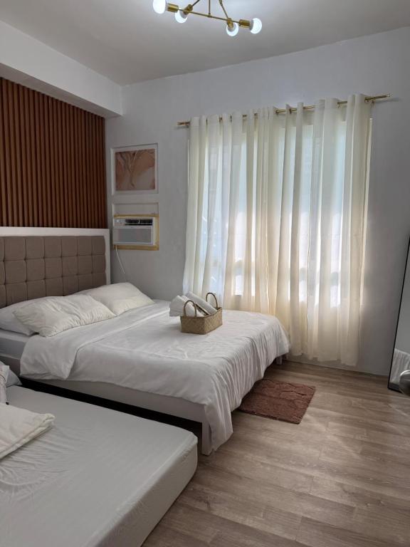 two beds in a bedroom with white curtains at Willow Nest in Bacolod