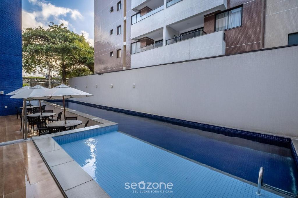 a swimming pool with tables and umbrellas next to a building at Apart in Condo w/ Pool and Gym STE0312 in Salvador
