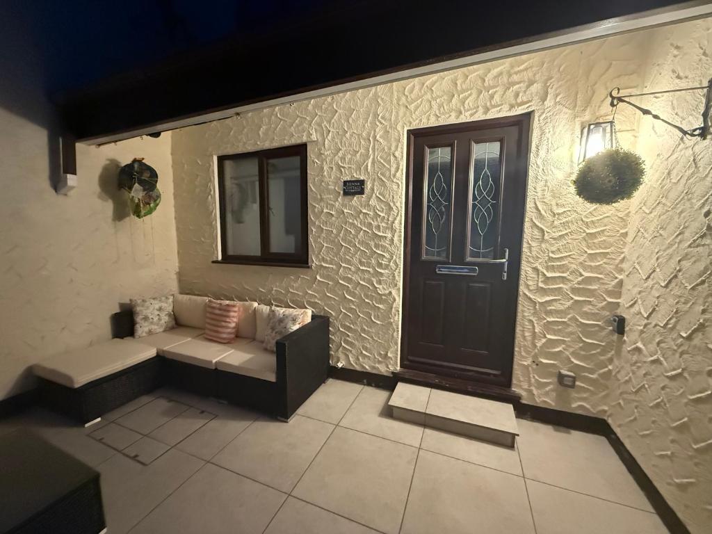 a living room with a couch and a door at Sienna Cottage in Benllech