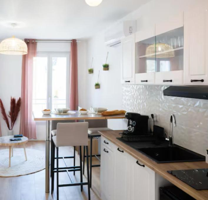 a kitchen with white cabinets and a counter top at L'écrin rose, appartement coeur de ville de Bergerac in Bergerac