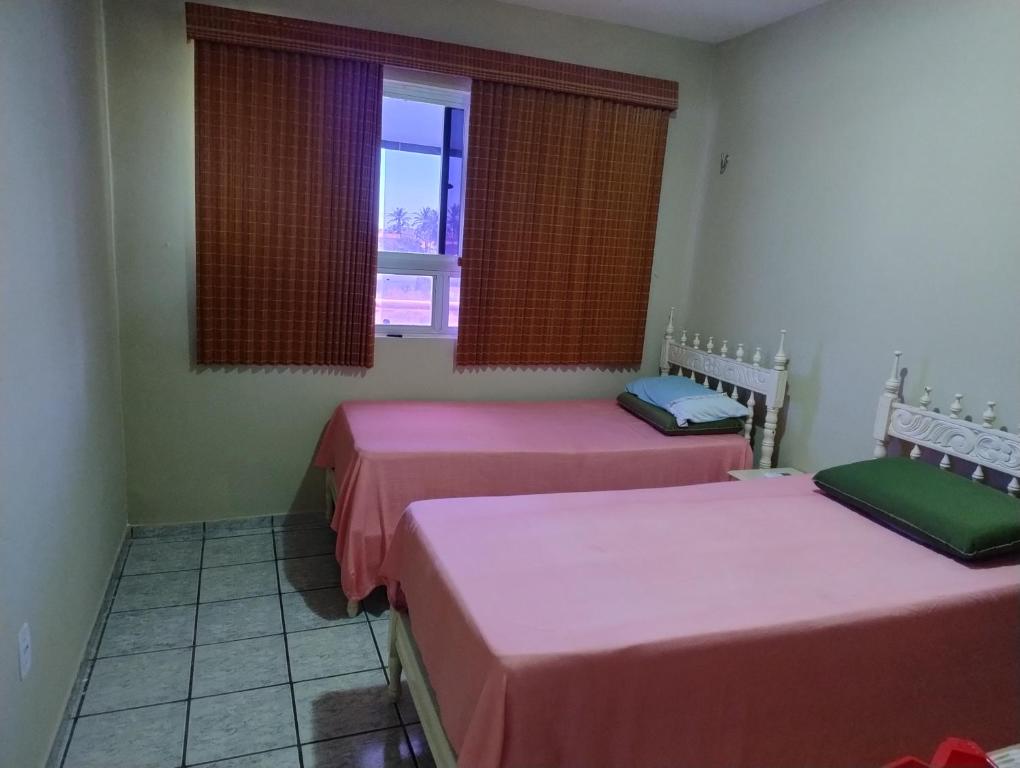 due letti in una stanza con finestra di Apartamento a Luis Correia