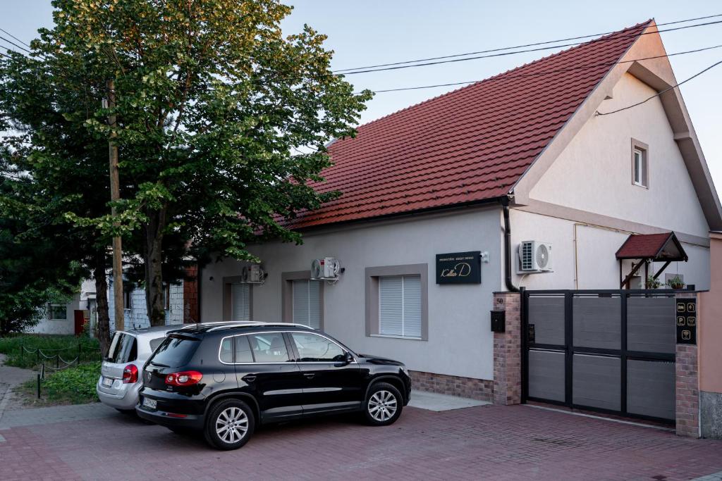 a black car parked in front of a house at Kollar D Guest House - Prenoćište ROOMS in Subotica