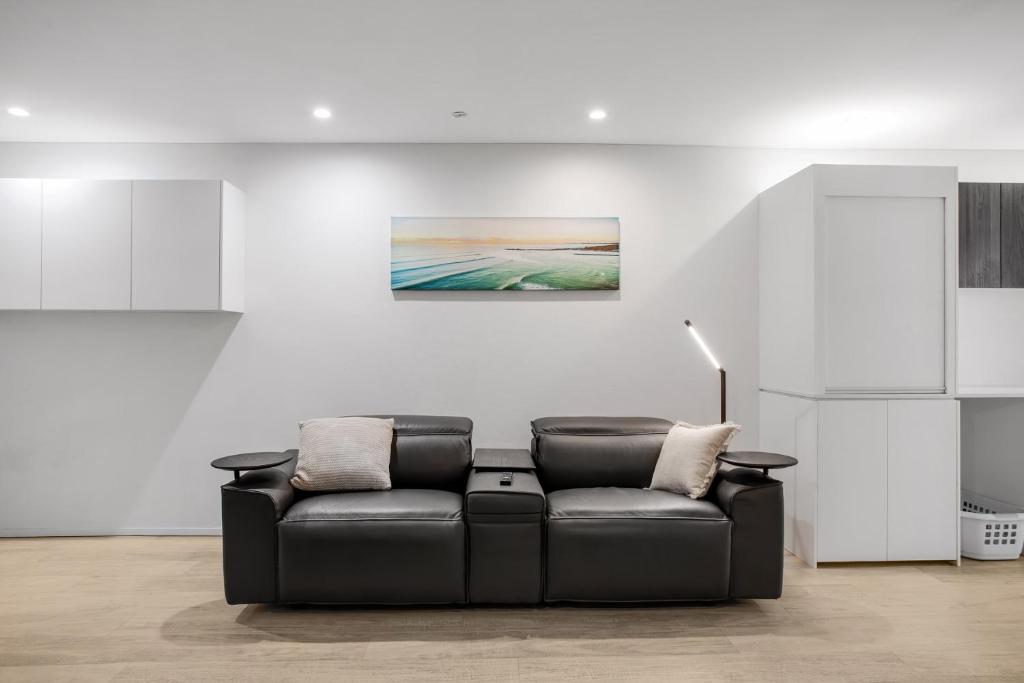 un canapé en cuir noir dans une pièce blanche avec un tableau dans l'établissement Arthur Street Apartments, à Gold Coast