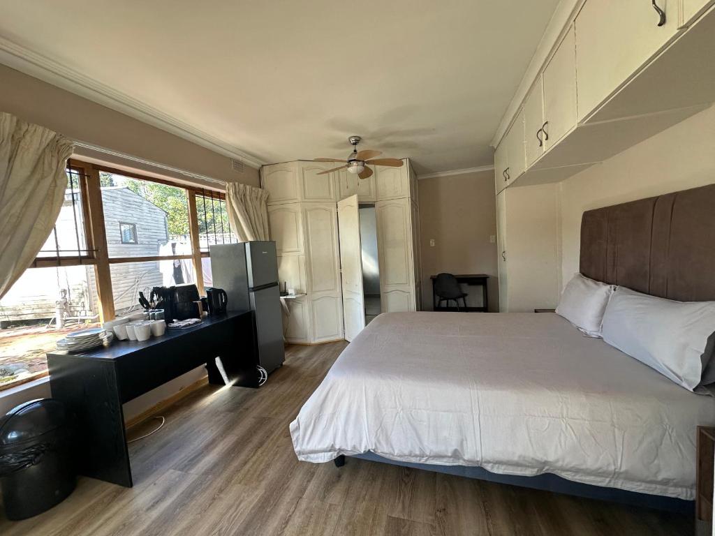 a bedroom with a bed and a desk and a window at Suite Dreams Garden Dream Cottage in Panorama