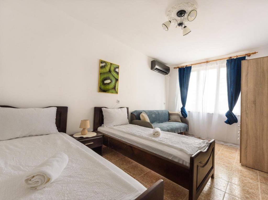 a bedroom with two beds and a chair and a window at Kiwi Apartment in Veliko Tŭrnovo