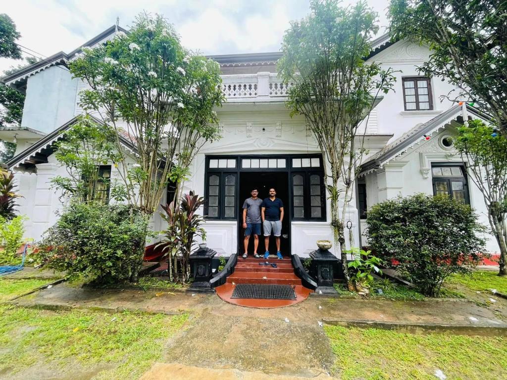 two people standing on the front of a house at Walauwa Bungalow in Katugastota