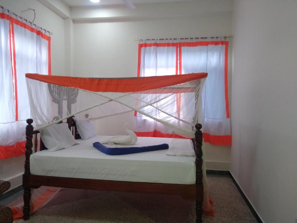 a bed with a canopy in a room with windows at Diamond Coast Apartment Paje in Paje