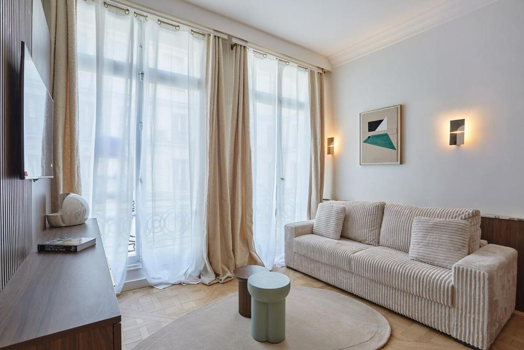un salon avec un canapé et une grande fenêtre dans l'établissement Apartment on the Champs Elysees, à Paris