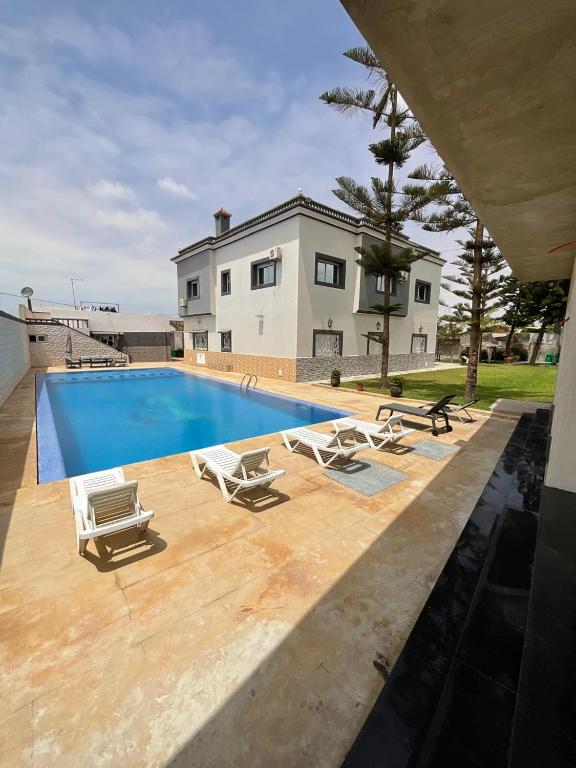 a swimming pool with lounge chairs and a house at Villa Royale Prestige Safaa in Dar Bouazza