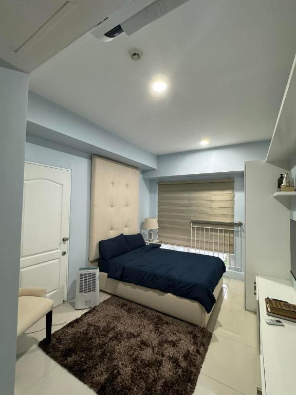 une chambre avec un lit aux murs bleus et un tapis dans l'établissement SMDC wind residences, à Kaybagal